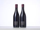 two bottles of red wine sitting on top of a table