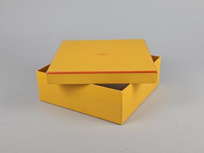 un gros plan d'une boîte jaune posée sur une surface blanche