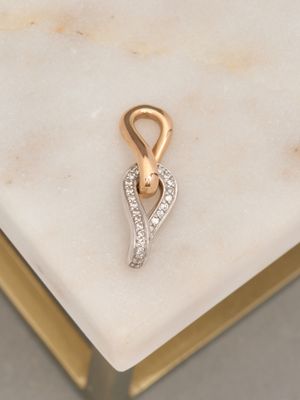 a close up of a gold and diamond pendant on a marble surface