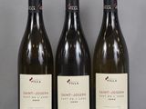 Trois bouteilles de vin sont alignées sur une table en verre