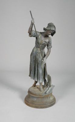bronze statue of a woman with a broom and a hat