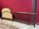 un lit avec une tête et un pied de lit en bois, adossé à un mur rouge
