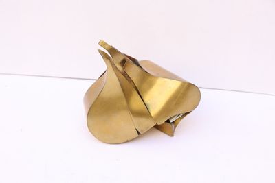 sculpture en laiton représentant une feuille sur une surface blanche