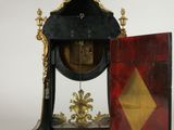 a clock that is sitting on a stand with a door open