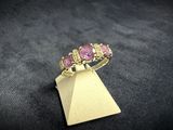 a close up of a gold ring with pink stones on it