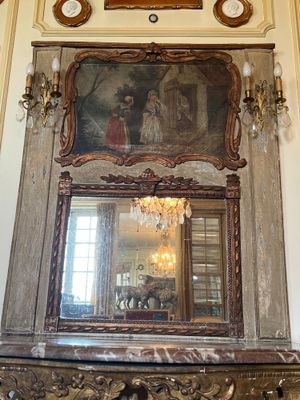 a mirror in the middle of a room with a painting on the wall