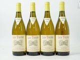 quatre bouteilles de vin sont alignées sur une surface blanche