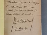 un livre ouvert, sur lequel est posée une note manuscrite, posé sur une table