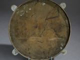 a brown plate on a stand on a gray surface