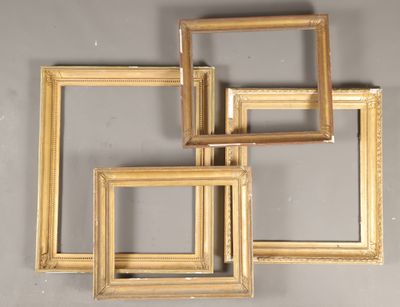 Quatre cadres dorés sont disposés sur un mur gris