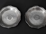pair of silver plated dishes on a black background
