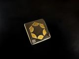 a close up of a gold plated square shaped object on a black surface