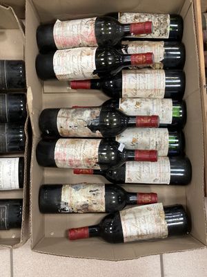 Plusieurs bouteilles de vin se trouvent dans un carton posé sur un sol carrelé.