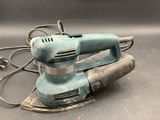 an electric sander sitting on top of a table next to a cord