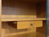 a wooden shelf with a glass door and a drawer underneath it