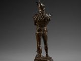 a bronze statue of a man holding a bird on a pedestal