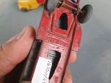a hand holding a red toy truck with a sticker on it
