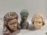three clay sculptures of a woman ' s head and a man ' s head
