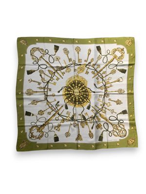 the square scarf has a gold and green design on it