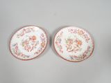 two plates with floral designs on them sitting on a table
