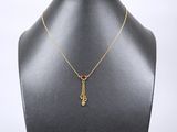 un collier plaqué or avec un pendentif en pierre rouge sur un mannequin