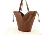 a brown leather tote bag sitting on top of a white bag