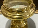 gold plated bowl on stand in front of a painting