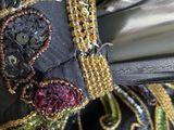 close up of a black dress with gold and red beads on it