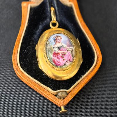 un cadenas doré sur lequel est représentée une femme en robe rose