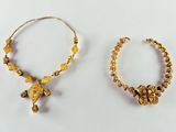 two pieces of gold jewelry on a white surface