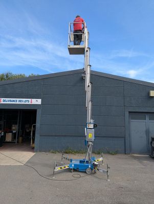 une photo d'un homme sur une nacelle élévatrice devant un immeuble