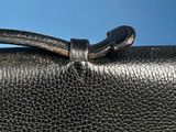 the handle of a black leather purse with a metal clasp