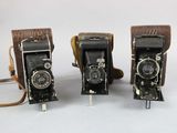 two old cameras are sitting side by side on a white surface