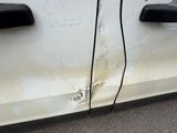 a white car that has been damaged and is parked on the side of the road