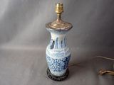 un vase bleu et blanc sur lequel est posée une lampe dorée