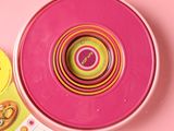 a pink bowl with a colorful design on it next to a package of donuts