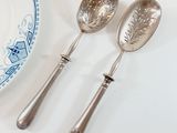two silver spoons and a plate on a table