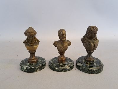 three brass figurines of a man and a woman on marble bases