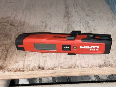 une image représentant un outil rouge et noir posé sur une table en bois