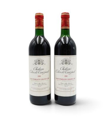 two bottles of red wine sitting next to each other on a white surface