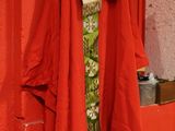 a red coat hanging on a red wall next to a toilet