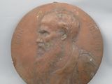 une image représentant une médaille de bronze sur laquelle figure le visage d'un homme