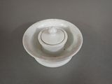 a white bowl with a lid sitting on a table