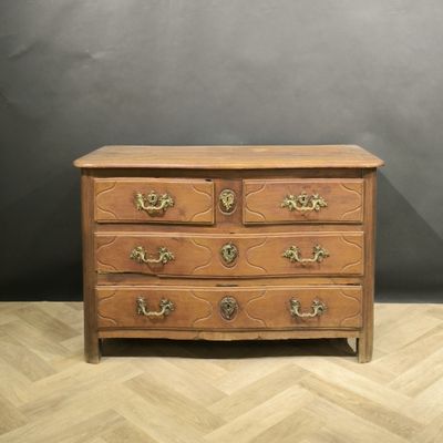 une commode ancienne posée sur un parquet, dans une pièce