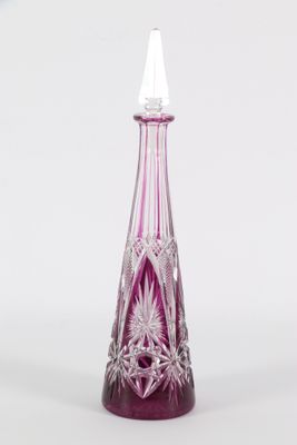 vase en verre violet et transparent, au sommet pointu, posé sur une surface blanche