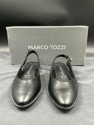 un gros plan sur une paire de chaussures noires posées sur un lit
