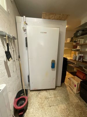 un réfrigérateur blanc dans une petite cuisine, avec une serpillière posée par terre