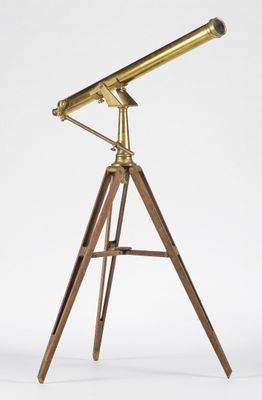 un télescope en laiton posé sur un trépied en bois, devant un fond blanc