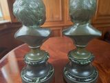 pair of bronze busts on pedestal on wooden table in room