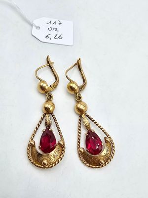 a pair of gold earrings with red stones on them